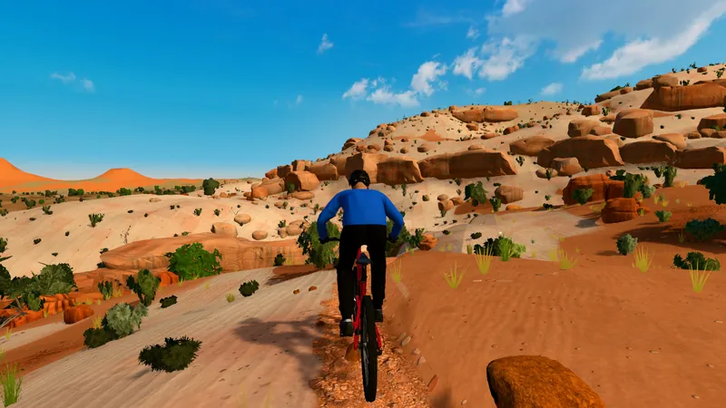Rider on Moab slickrock below sandstone ledges, boulders and juniper